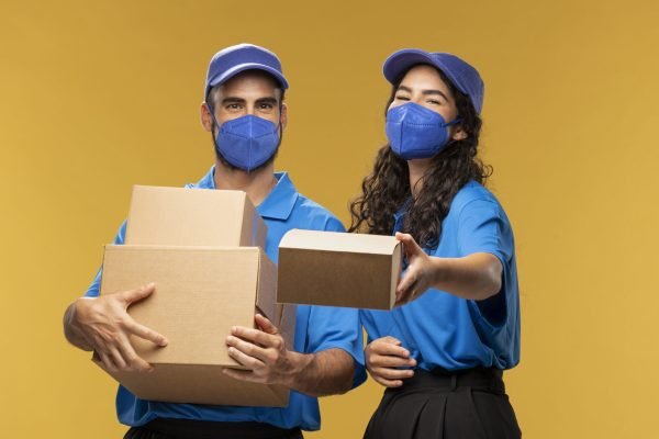 portrait-male-female-deliverers-with-medical-masks-handing-out-cardboard-box